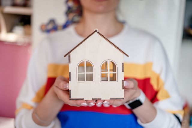 a person holding a small wooden house